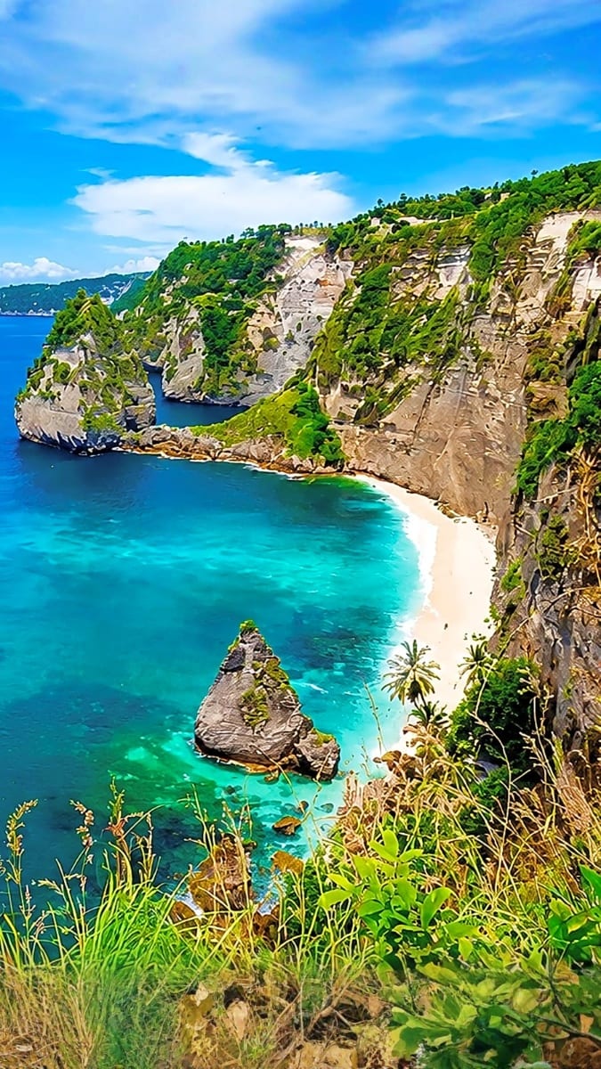 Dramatic coastal cliffs with turquoise waters and white sand beach at Kelingking Beach, Nusa Penida, Bali