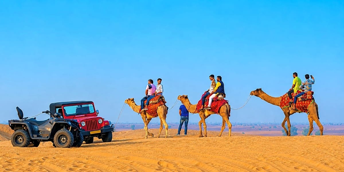 Tourists riding camels on golden sand dunes in Jaisalmer desert with red Jeep and clear blue sky
