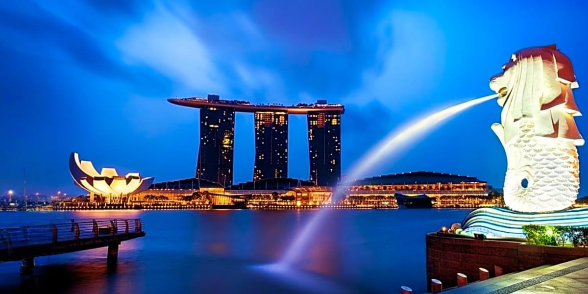 Merlion statue with Marina Bay Sands hotel illuminated at twilight in Singapore's Marina Bay