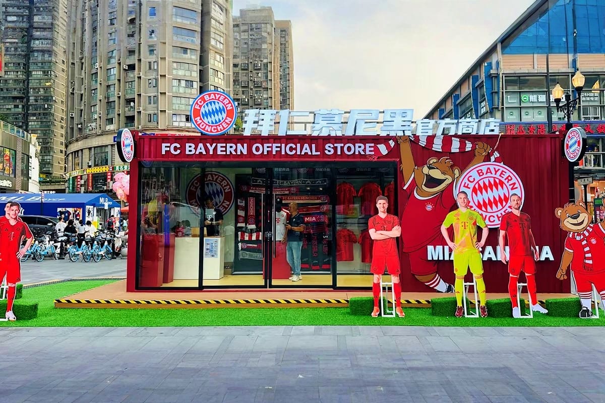 FC Bayern Munich official store with red and white branding, mannequins in team uniforms, and city buildings in background