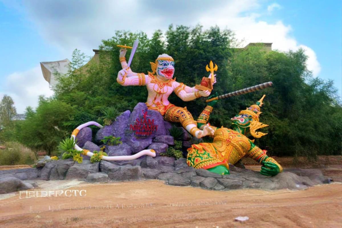 Siam Niramit Show Colorful Thai mythological demon statue with sword and trident at Siam Niramit Show entrance surrounded by trees