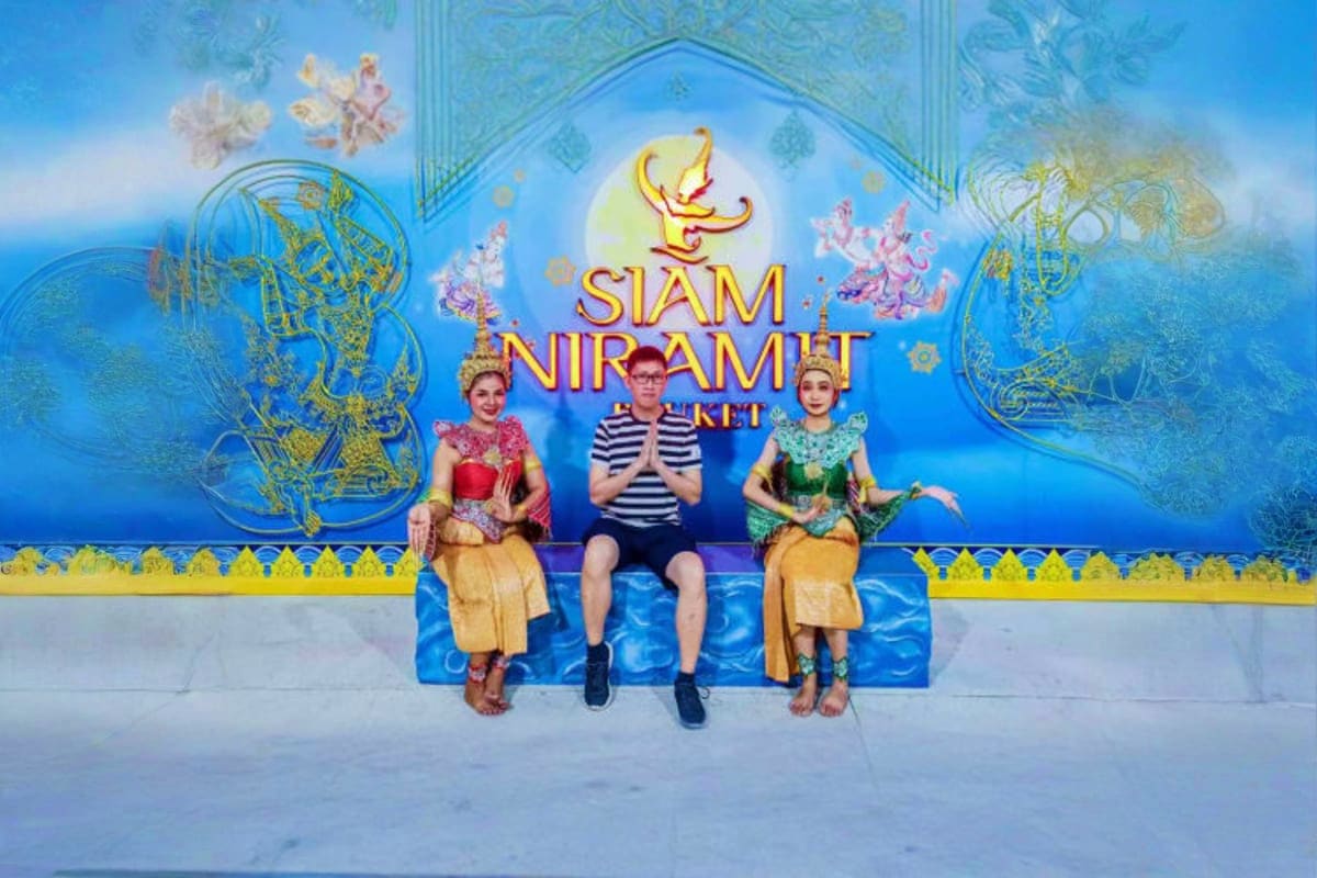 Siam Niramit Show Three visitors posing in front of Siam Niramit Show blue entrance backdrop with Thai cultural decorations and signage