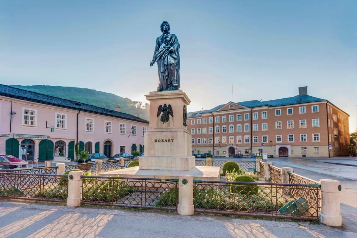 Munich to Salzburg Sightseeing Day Trip By Train Mozart statue in Salzburg town square with historic buildings and mountains in background
