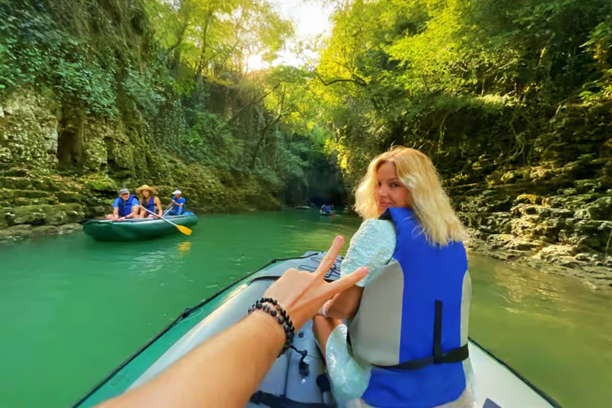 Martvili Canyon and Prometheus Cave Group Tour Woman in blue life jacket kayaking through turquoise waters of Martvili Canyon surrounded by limestone cliffs and lush green