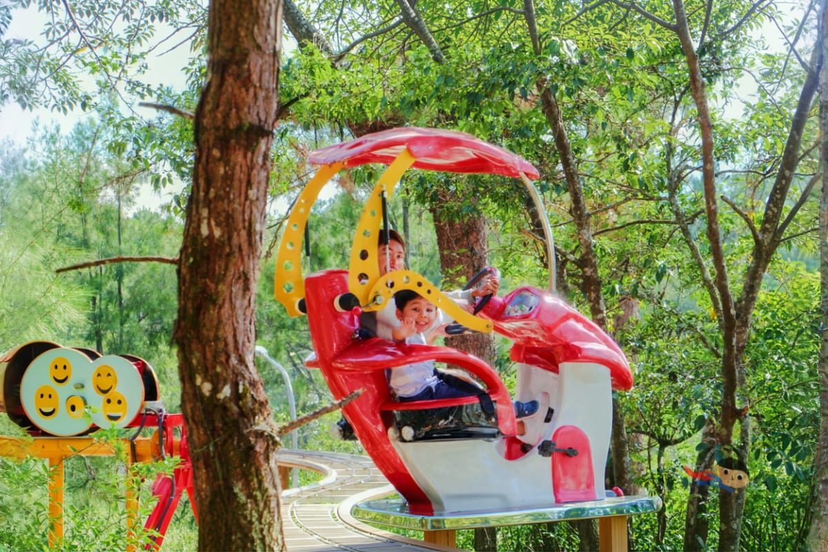 Sky Ranch Baguio Ride All You Can Day Pass Child riding red and yellow ladybug-shaped ride at Sky Ranch amusement park surrounded by tall trees