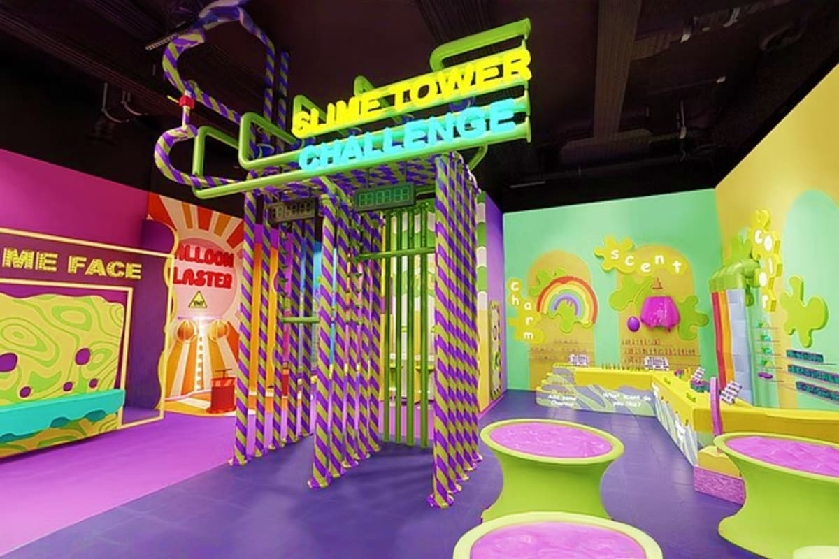 Colorful indoor play area with neon signage, purple and lime green architectural elements, and interactive installations at G