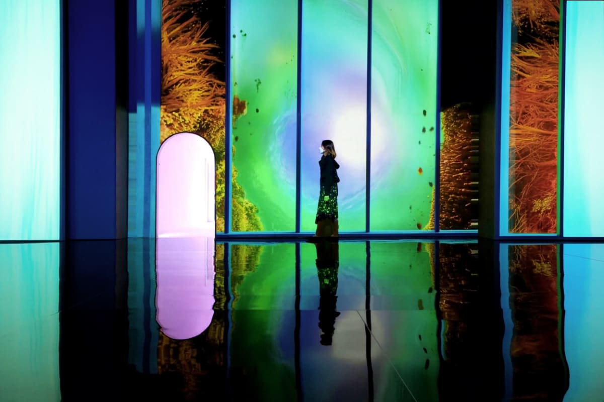 Art In Island The Media Square Person standing in modern art installation with colorful illuminated panels and reflective floor at Art In Island The Media S