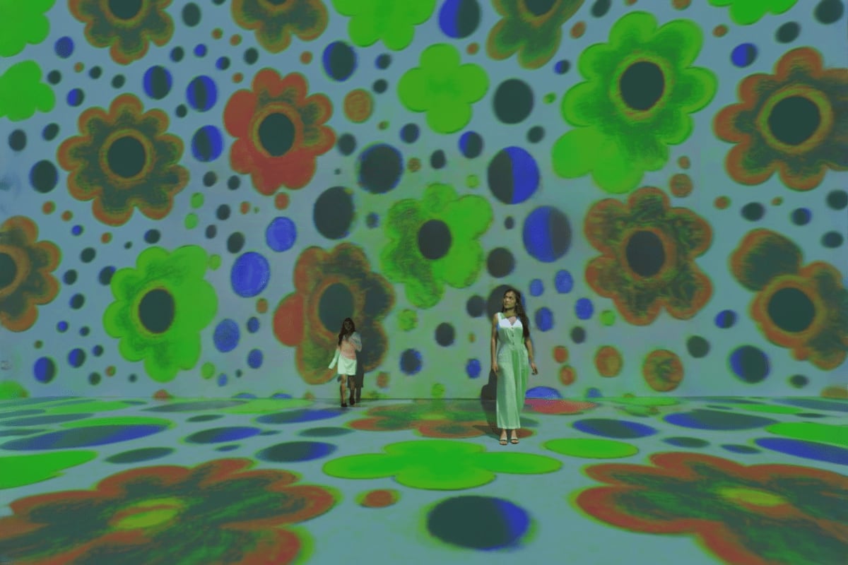 Art In Island The Media Square Two visitors standing in immersive digital art installation with projected colorful flowers and geometric patterns on walls a