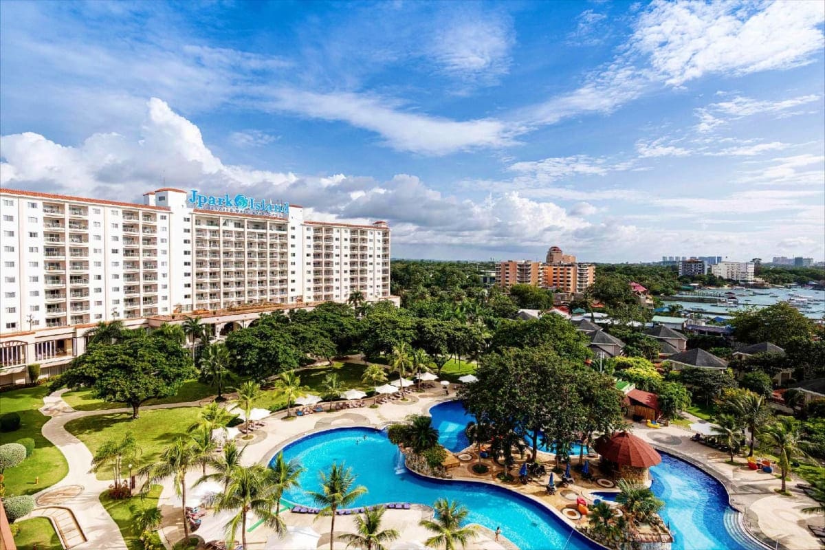 Jpark Island Resort white apartment buildings with blue resort pools, palm trees, and river waterway in tropical setting