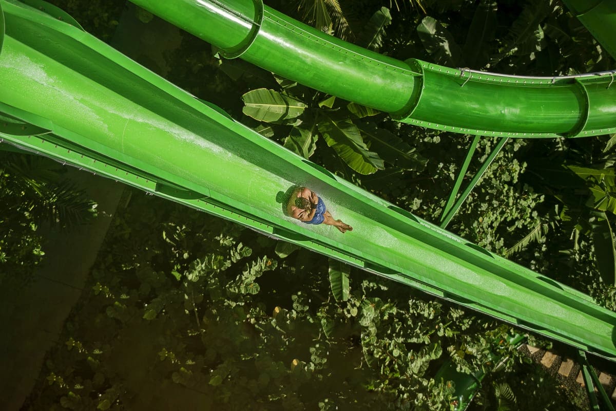 Waterbom Bali Person sliding down green water slide at Waterbom Bali with tropical foliage visible in background