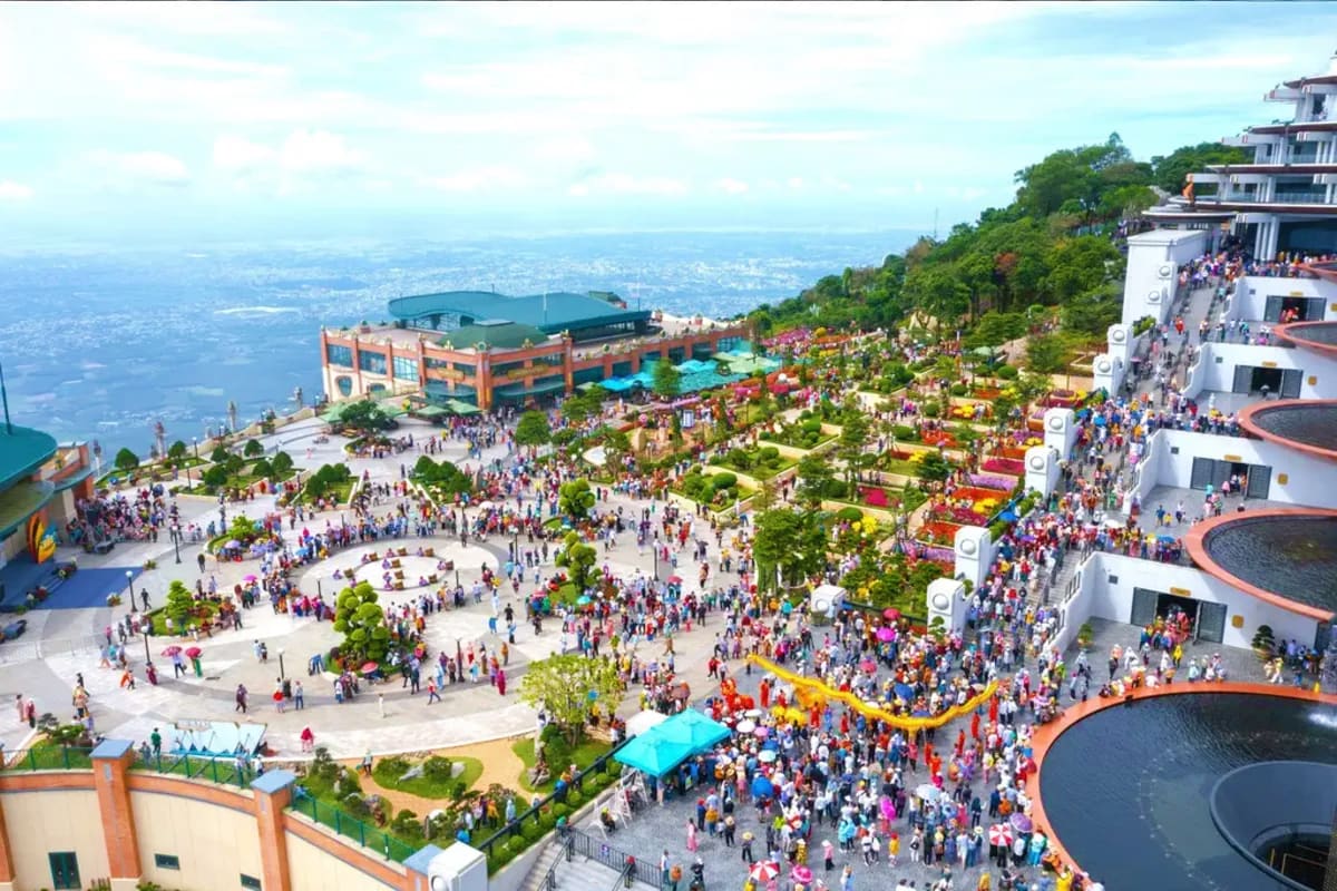 Aerial view of Sun World Ba Den amusement park with crowded plazas, gardens, attractions, and mountainous landscape in backgr