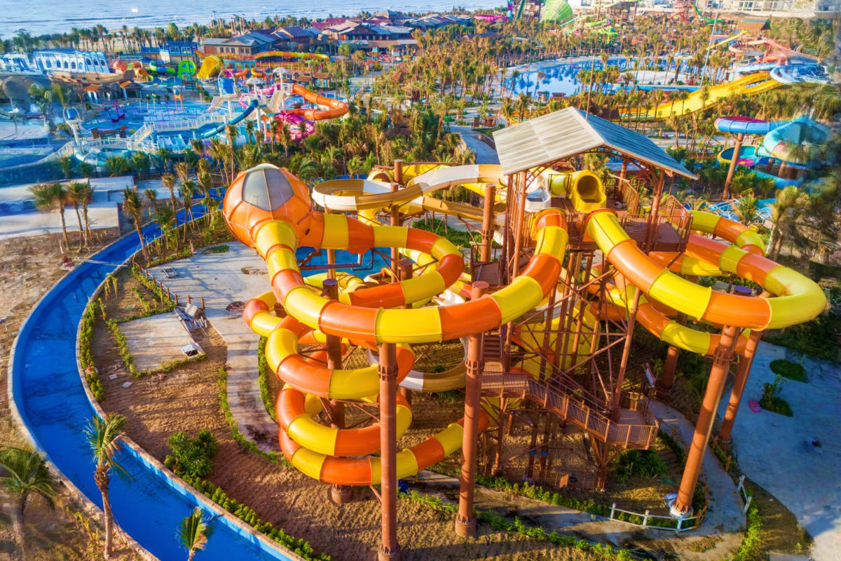 Aerial view of Sun World Vung Tau water park with orange and yellow spiral water slides, blue pools, palm trees, and colorful