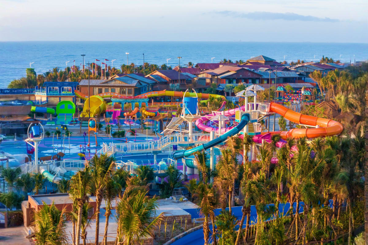 Aerial view of Sun World Vung Tau water park with colorful slides, pools, palm trees, and seaside buildings overlooking the o