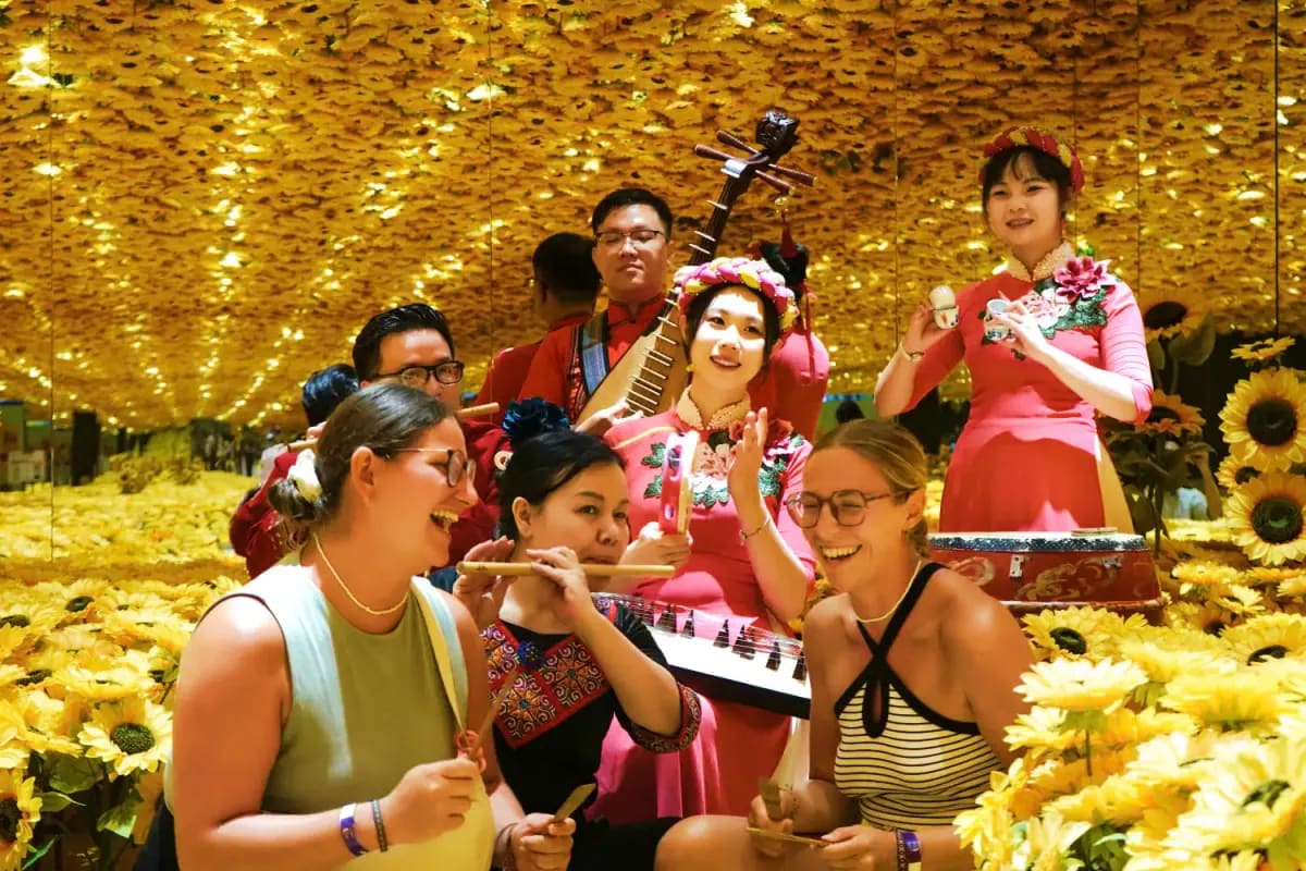 Metashow Exhibition Group of musicians performing with traditional instruments in front of golden glittering wall decorated with sunflowers at Me