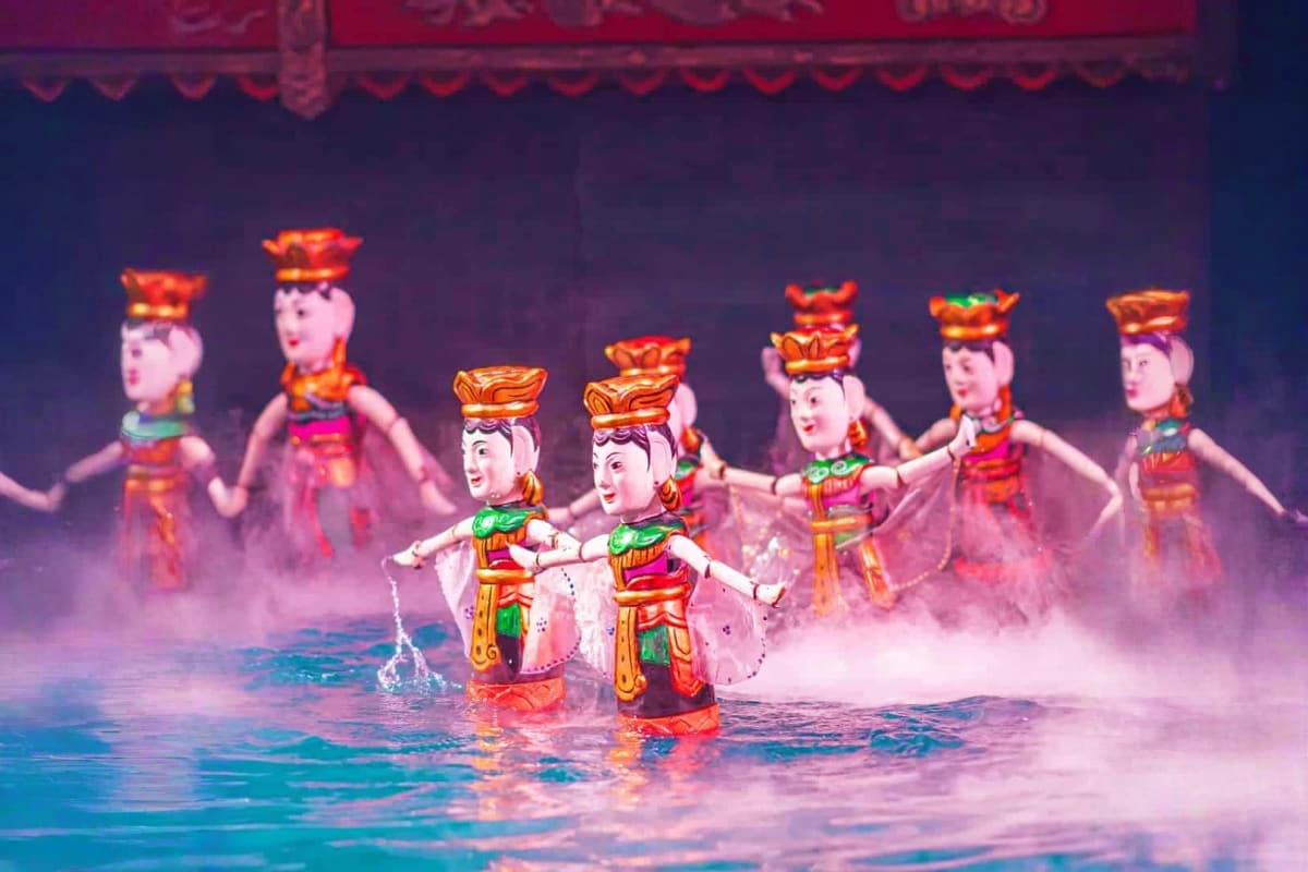 Water Puppetry Show and Dinner On Cruise Traditional Vietnamese water puppets performing in colorful costumes on stage with water and mist effects during a puppet the