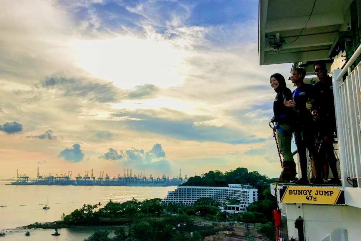 AJ Hackett Sentosa People preparing for bungee jump at AJ Hackett Sentosa with view of harbor, cruise ship, and port cranes in Singapore