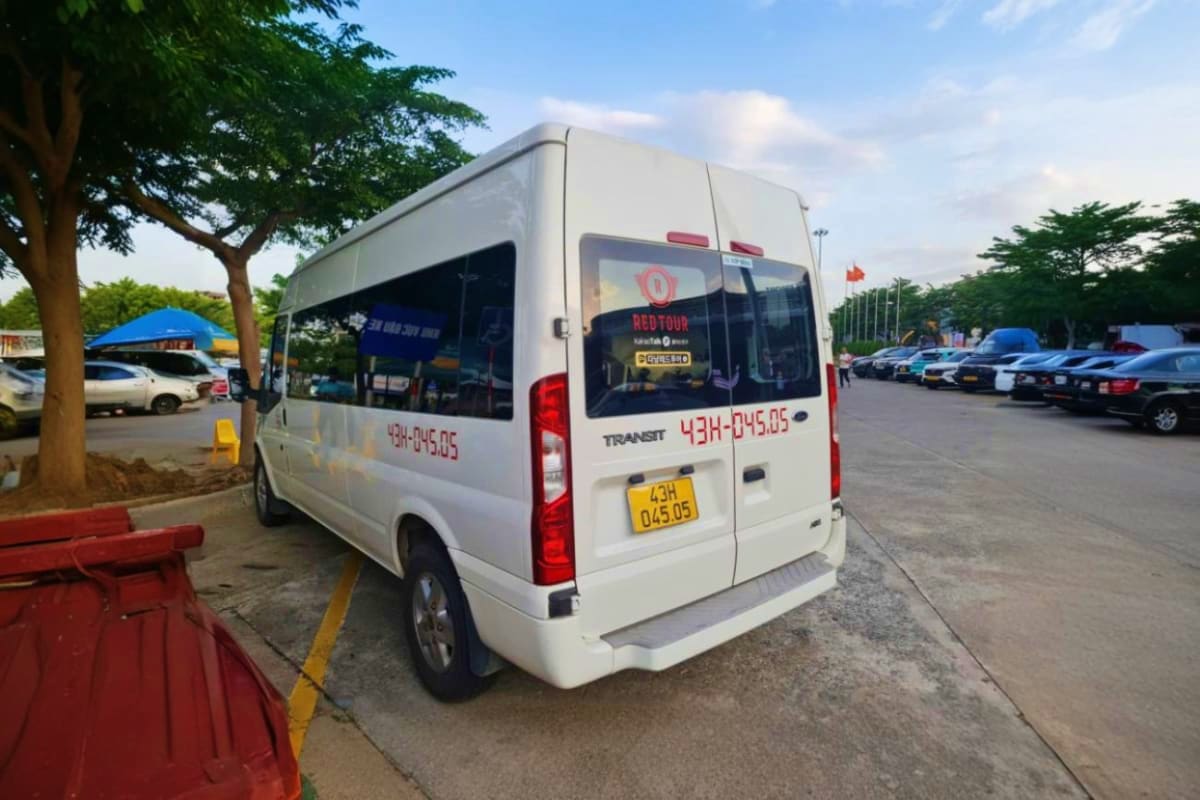 Ho Chi Minh Airport Pickup White Ford Transit van with Red Tour branding parked in lot, used for Ho Chi Minh Airport pickups and transfers