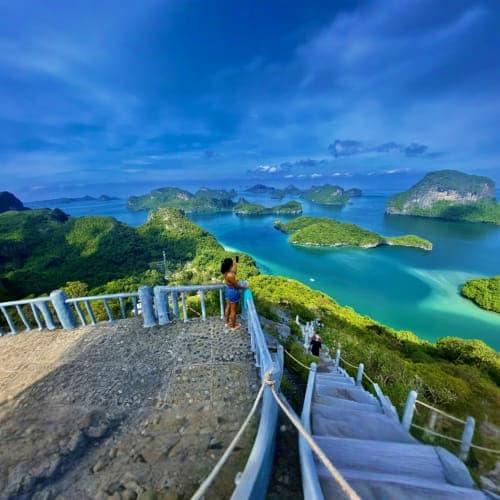 Tourist viewing turquoise waters and limestone islands from elevated viewpoint at Angthong National Marine Park, Thailand