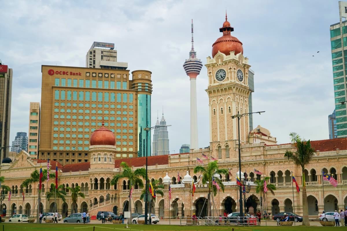 Combo tour of Kuala Lumpur City with Batu Caves and Fireflies Trip Sultan Abdul Samad Building with clock tower and Kuala Lumpur skyline, featuring colonial architecture and modern skyscrapers