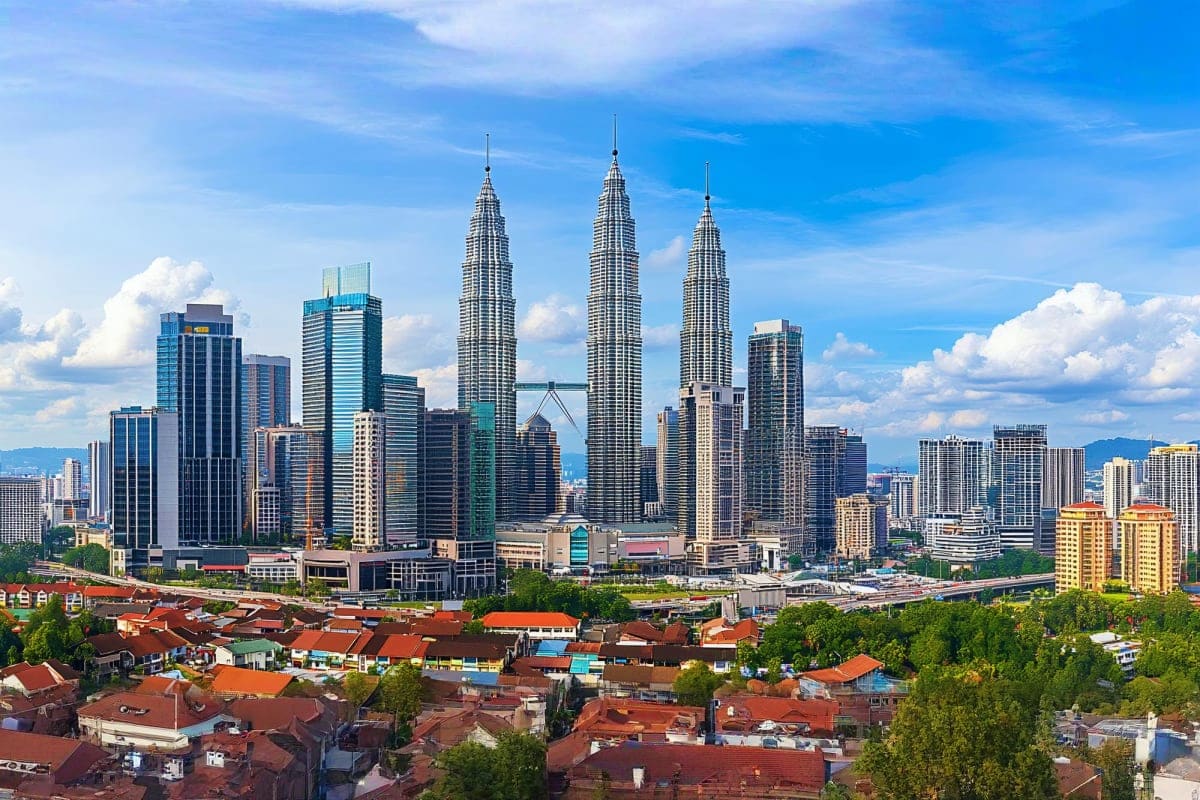 Combo tour of Kuala Lumpur City with Batu Caves and Fireflies Trip Kuala Lumpur skyline featuring Petronas Twin Towers and city skyscrapers with residential buildings and green areas in foregr