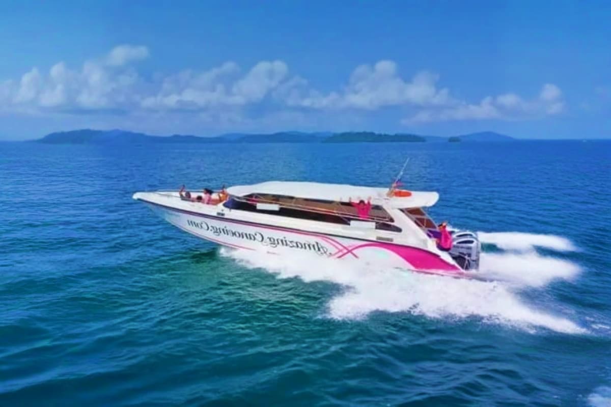 Coral Island on Speed Boat with Lunch White and pink speed boat with passengers cruising through turquoise ocean water toward distant islands under blue sky