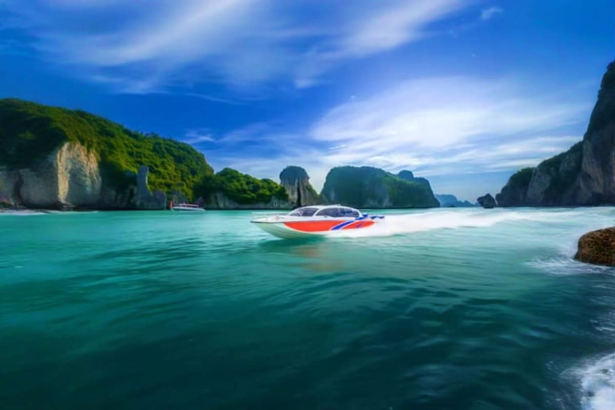 Speed boat with red and blue striped canopy anchored in turquoise waters surrounded by limestone cliffs and lush green hills