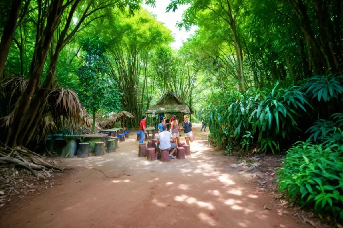 Visitors gather at a shaded rest area along a tree-lined path at Cu Chi Tunnels historical site in Vietnam
