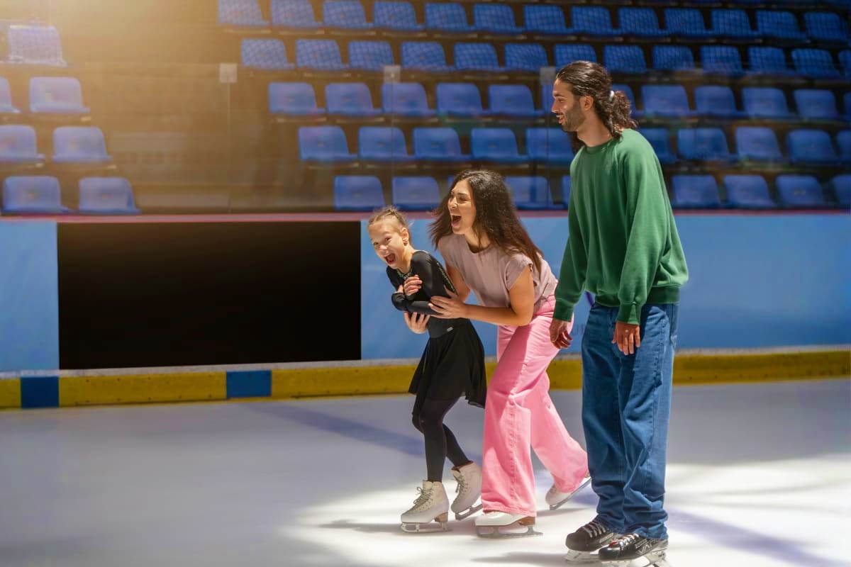 Family enjoying ice skating at Dubai Ice Rink with young child learning to skate while adults provide support