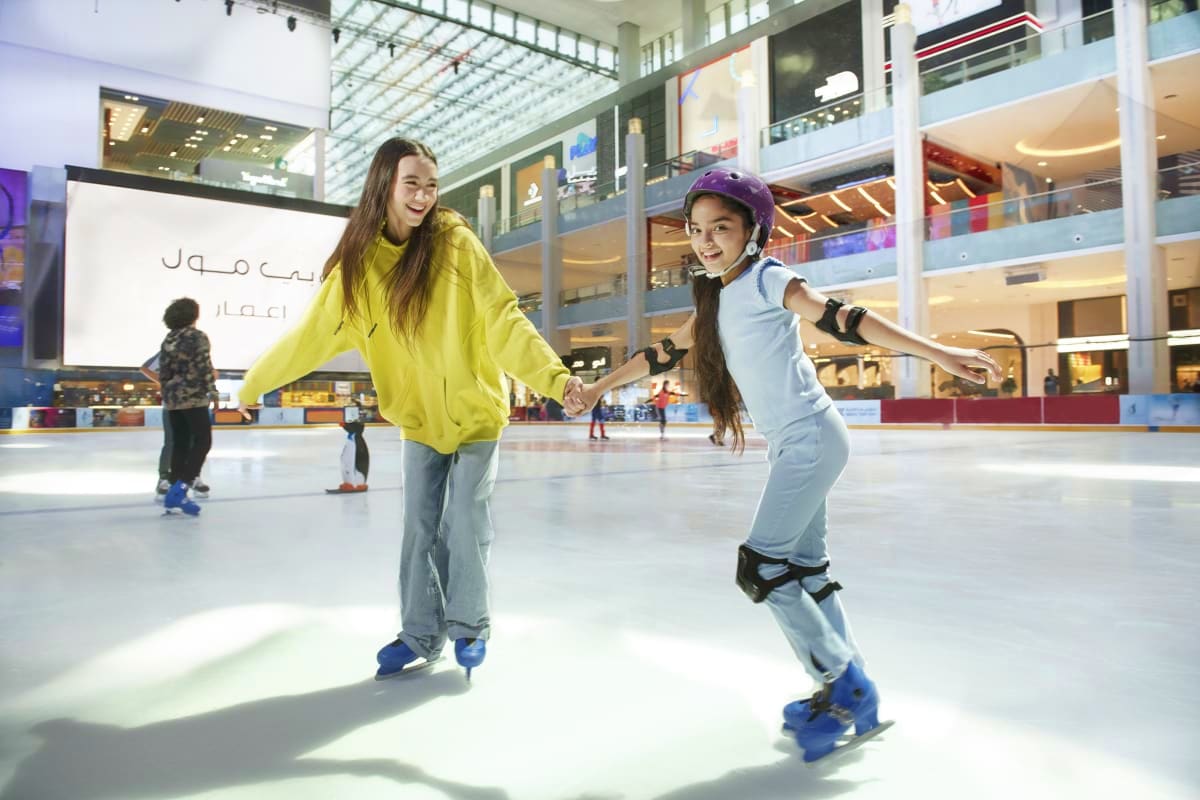 Dubai Ice Rink Two young girls ice skating hand-in-hand at Dubai Ice Rink, a modern indoor skating venue with multi-level glass architecture