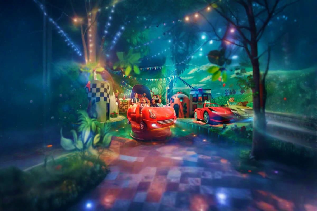 Illuminated Ferrari-themed attraction at night with red race cars, checkered flags, and glowing decorative lights in an indoo