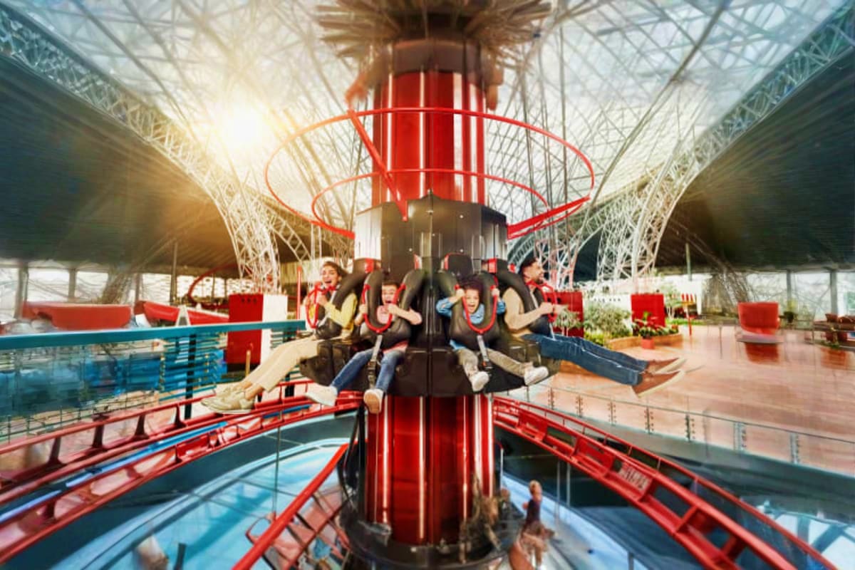 Ferrari Theme Park Abu Dhabi Visitors riding a red and black spinning ride with extended arms at Ferrari Theme Park Abu Dhabi indoor facility