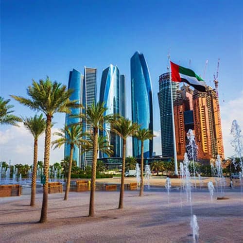 Abu Dhabi city skyline with modern skyscrapers, UAE flag, palm trees, and fountain in public plaza