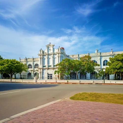Penang Town Hall, a grand white colonial building with clock tower and manicured gardens, under blue sky