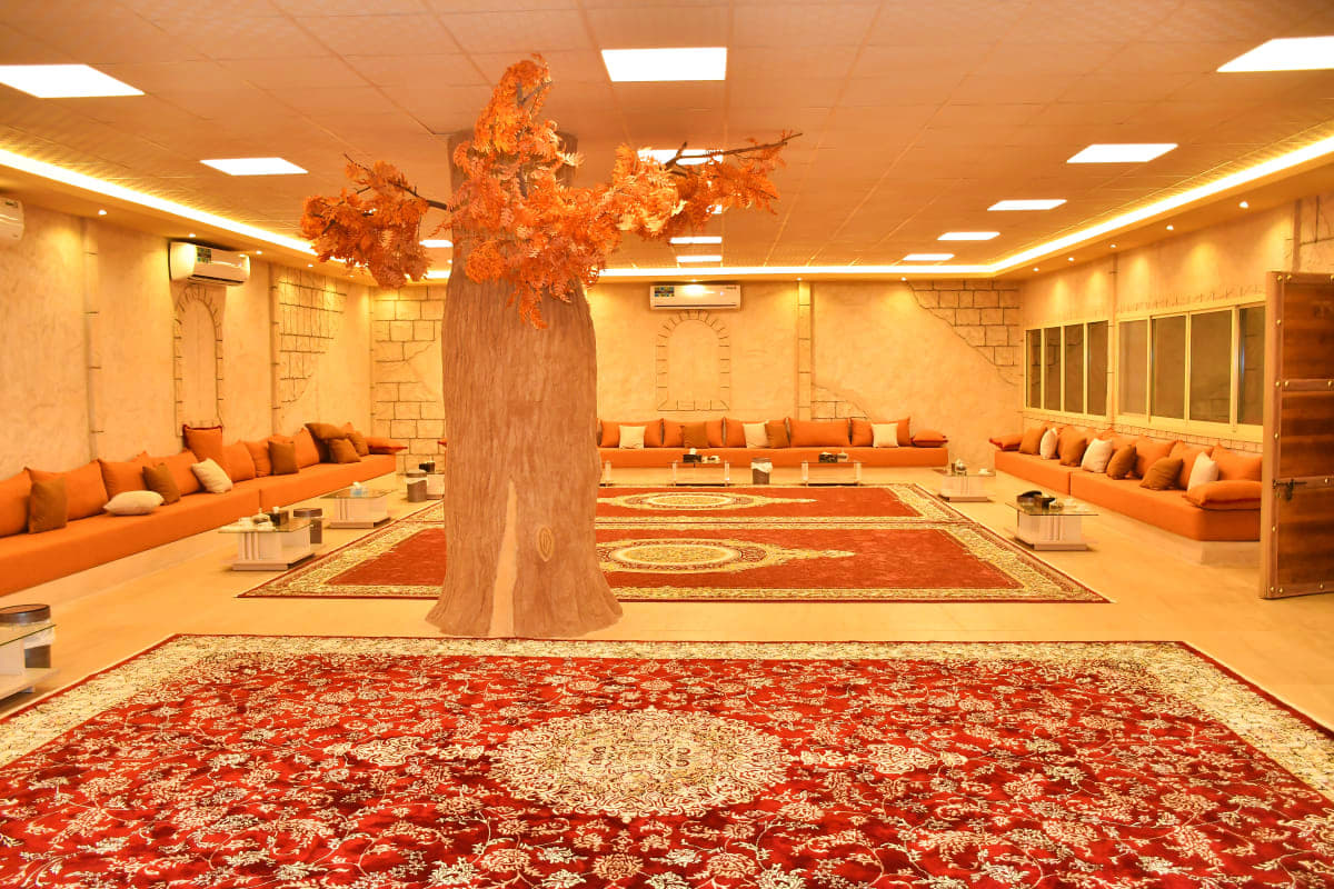 Luxurious orange-themed lounge interior with decorative tree and traditional red patterned rugs in Dubai hospitality space