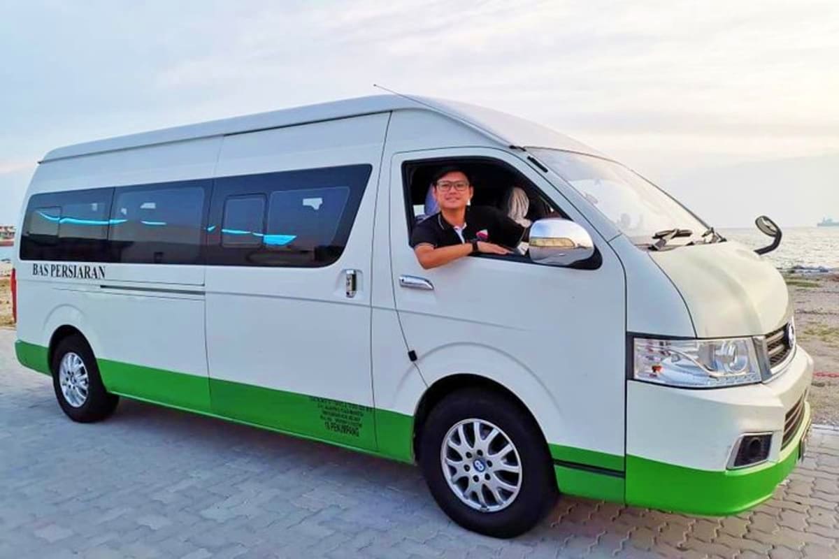 Kuala Lumpur to Cameron Highlands Intercity Transfer Driver sitting in white and green intercity transfer van at coastal pier with ocean in background