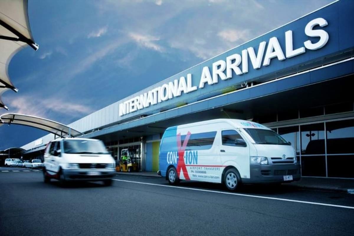 Airport transfer vehicles parked at international arrivals terminal with shuttle van ready for passenger pickup