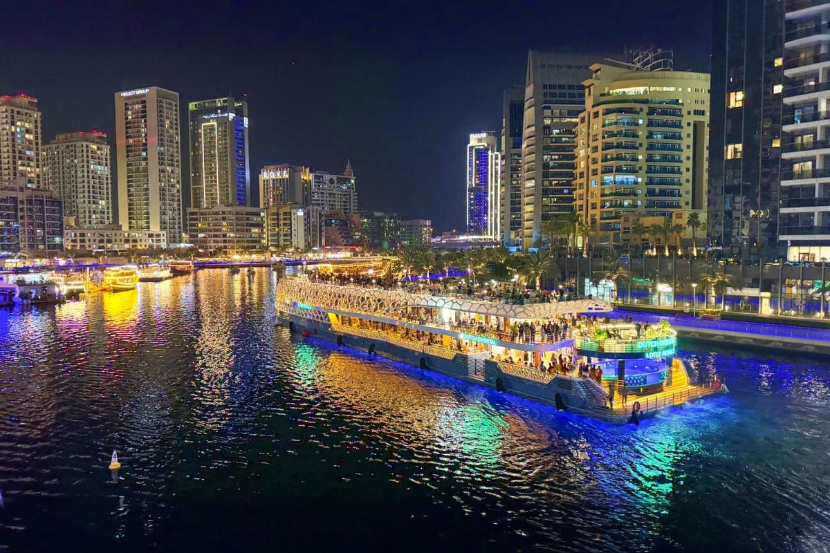 Lotus Mega Yacht Dinner Cruise Illuminated dinner cruise yacht on waterway at night with downtown skyline and tall buildings reflected in water