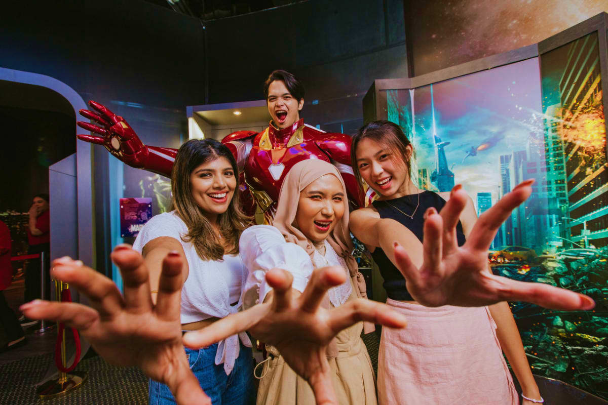 Madame Tussauds Singapore Group of visitors posing with Iron Man wax figure at Madame Tussauds Singapore museum with cityscape backdrop