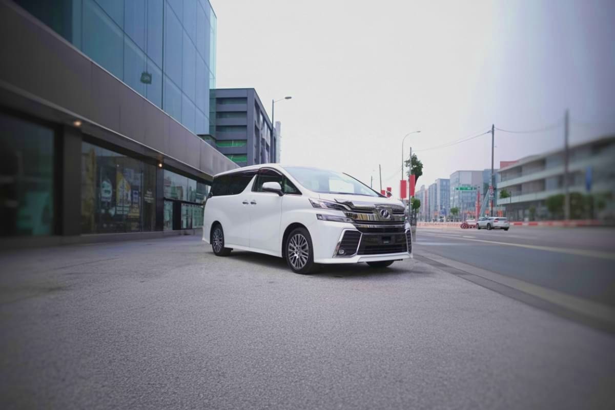 White Lexus minivan parked on urban street with modern buildings and city skyline in background