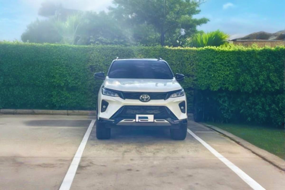 White Toyota SUV parked in driveway with green hedges, representing intercity transfer vehicle service from Malacca to Kuala