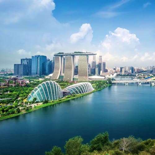 Aerial view of Marina Bay Sands hotel and Supertree Grove with Singapore skyline reflected in blue waterfront