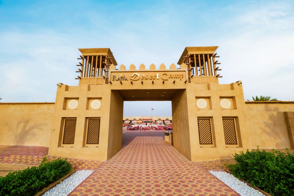Entrance gate to Desert Camp with tan-colored fort-style architecture and patterned brick pathway leading through the archway
