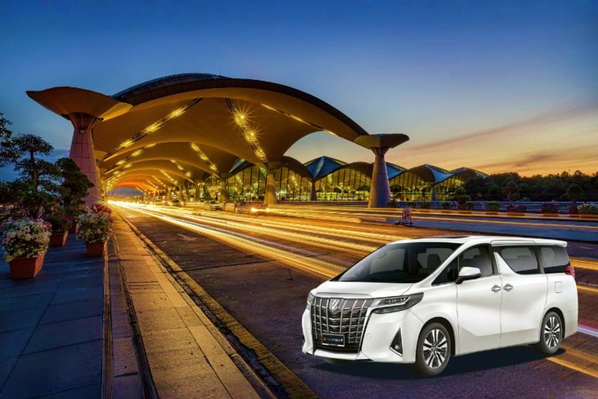 White luxury minivan parked under illuminated yellow futuristic architecture at Kuala Lumpur Airport terminal at dusk