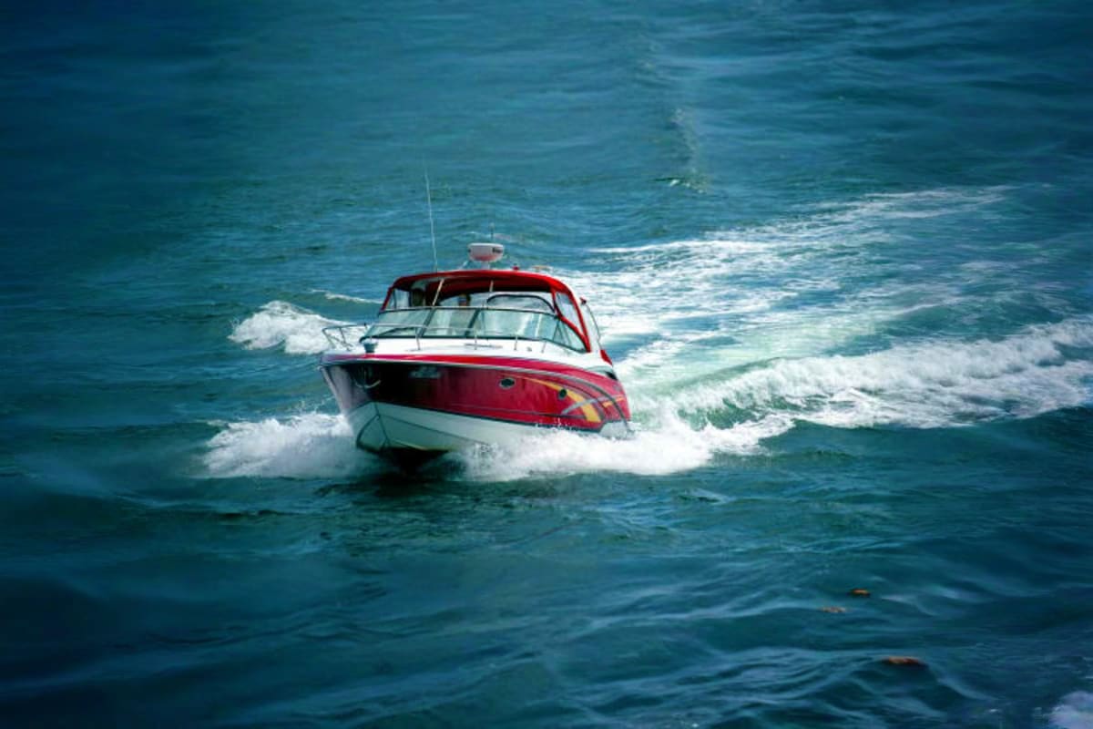 Red and white speedboat riding waves near Phi Phi Island with turquoise ocean and white-capped waves in background