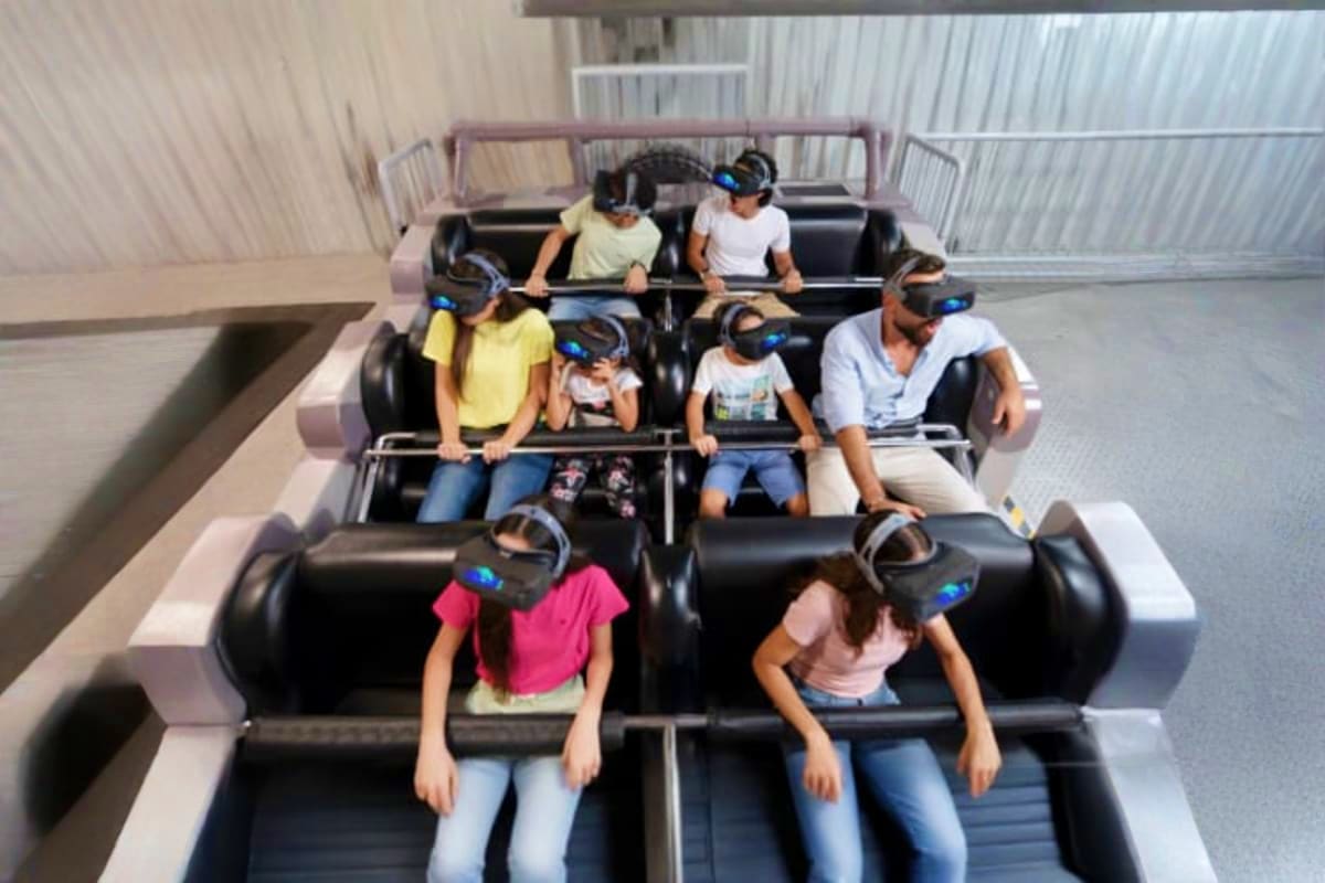 Group of visitors wearing VR headsets on black roller coaster seats at Play DXB indoor theme park in Dubai
