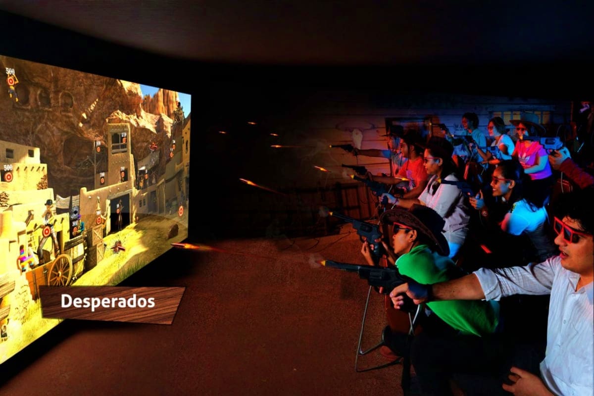 Group of visitors playing interactive light gun game at Sentosa 4D AdventureLand with Desperados Western-themed display on sc