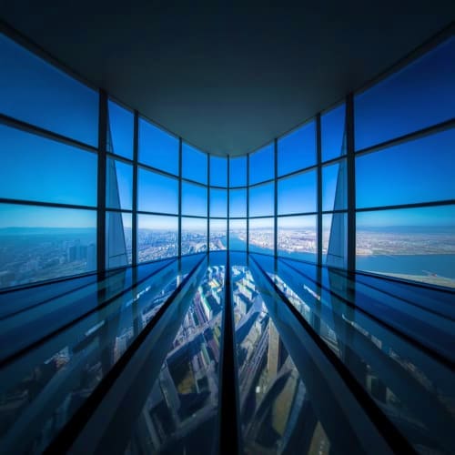 View from Burj Khalifa observation deck showing floor-to-ceiling windows with cityscape and landscape visible below