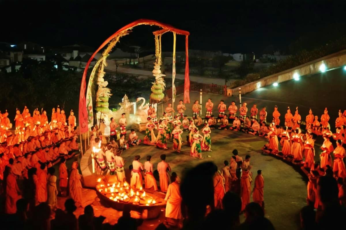 Buddhist monks in orange robes gathered around lit candles during Kecak fire dance ceremony at night temple festival