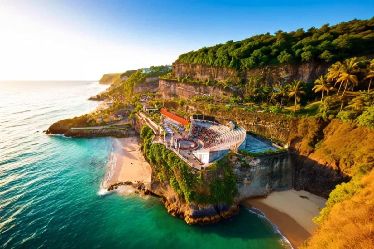 Uluwatu Temple perched on clifftop overlooking turquoise ocean with amphitheater stage for Kecak dance performance below