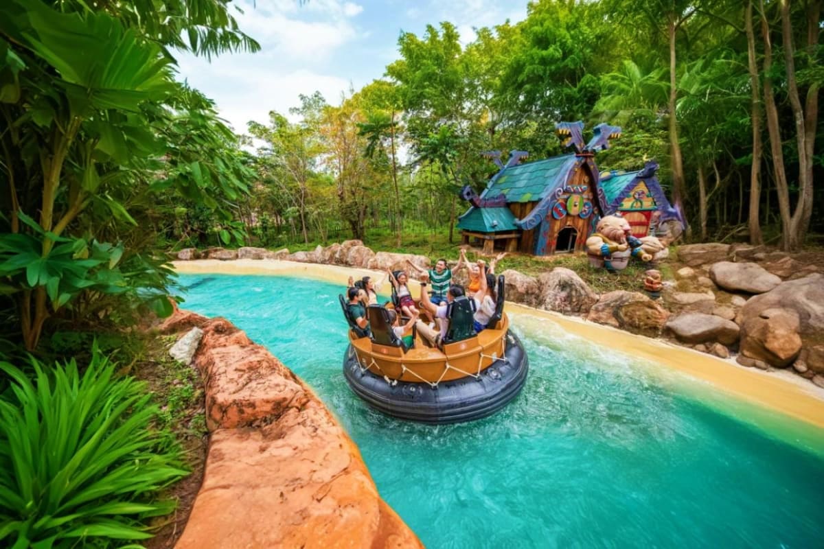 VinWonders Grand Park Ho Chi Minh Guests riding an inflatable boat attraction in turquoise water at VinWonders Grand Park Ho Chi Minh, surrounded by tropical j